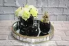 Decorative items on a mirrored tray against a brick wall. Produktbild-Vorschau