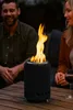 Two people sitting at a table outdoors at night, with a portable fire pit in the center. Produktbild-Vorschau