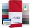 A stack of folded bed sheets in various colors, with a red sheet prominently displayed in the foreground, featuring product branding and certifications. Anteprima dell’immagine prodotto