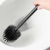 A hand holding a black toilet brush over a white toilet bowl. Náhled obrázku produktu