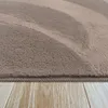 A close-up view of a fluffy rug with a wave pattern, resting on a wooden floor. Produktbild-Vorschau