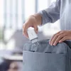 A person is placing a white USB charger into a grey bag. Náhled obrázku produktu