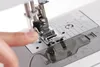 Close-up view of a sewing machine's presser foot being operated by a finger. Produktbild-Vorschau