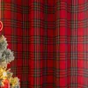A close-up of a red plaid curtain with a Christmas tree branch in the foreground. Produktbild-Vorschau