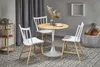A small round dining table with three white chairs in a room with a patterned rug and curtains. Produktbild-Vorschau