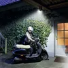 A person in a helmet is about to ride a scooter under an outdoor light. Produktbild-Vorschau