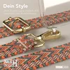 A close-up of a phone case strap with a patterned design and gold hardware, attached to a clear phone case. Produktbild-Vorschau