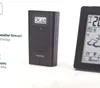Two weather stations are shown against a white background. The one on the left is a black Hama device with a digital display showing '25.060'. The one on the right is a black framed device with a digital display showing weather information. Anteprima dell’immagine prodotto