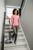 A woman walks down a staircase holding a cordless floor washer. Produktbild-Vorschau