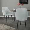 Two dining chairs are placed around a round dining table in a room with gray walls and a wooden floor. Produktbild-Vorschau