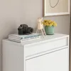 A close-up view of a white cabinet with decorative items on top. Produktbild-Vorschau