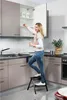 A woman is using a step stool to reach items in a kitchen cabinet. Produktbild-Vorschau