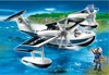 A toy police seaplane flying over water with a toy police officer standing on the shore. Produktbild-Vorschau