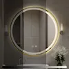 A round LED mirror with a gold frame is shown in a bathroom setting. The lighting of the mirror is adjustable, indicated by the gradient overlay and percentage markers. Produktbild-Vorschau
