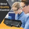 Two women in lab coats and safety glasses examining a printer toner cartridge. Produktbild-Vorschau