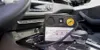 A tire repair kit with a compressor is placed on the center console of a car. Produktbild-Vorschau