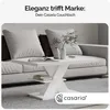 A white coffee table with books and vases on it, placed in front of a sofa in a living room. Produktbild-Vorschau