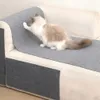 A cat is scratching a sofa that has protective mats on it. Produktbild-Vorschau