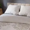 A close-up view of a bed with beige bedding and pillows. Podgląd zdjęcia produktu