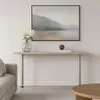 A console table with decorative items and a painting above it, next to a sofa. Voir les images du produit
