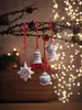 Christmas ornaments hanging from a branch with bokeh lights in the background. Produktbild-Vorschau