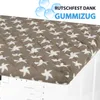 A close-up view of a quilted cover with a bird pattern, placed on top of a washing machine. Podgląd zdjęcia produktu