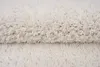 A close-up view of a fluffy, cream-colored rug. Voir les images du produit