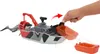 A hand is shown interacting with a toy rescue boat that has a shark and a cage attached. Náhľad obrázku produktu