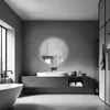 A modern, minimalist bathroom with a freestanding bathtub, a vanity with a sink and mirror, and a tall storage unit. Podgląd zdjęcia produktu