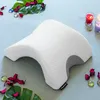 A white and gray orthopedic pillow for couples is displayed on a light blue striped surface, surrounded by decorative elements like green leaves, red petals, and small candles. Anteprima dell’immagine prodotto