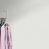 A clothing rack with pink and gray garments hanging on it, set against a textured light gray background. Produktbild-Vorschau