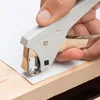A hand is using a stapler remover to remove staples from a piece of paper on a wooden surface. Anteprima dell’immagine prodotto