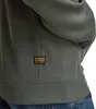 A close-up view of the bottom hem and a label on a green hooded jacket. Produktbild-Vorschau