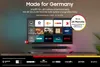 A Samsung QLED TV is displayed on a stand, showcasing various streaming service logos and promotional text. Voir les images du produit