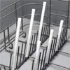 A close-up view of white cylindrical objects placed vertically in a gray metal rack, likely a dishwasher basket. Produktbild-Vorschau