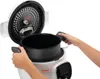A person is holding a multi-functional cooker with the lid open. Podgląd zdjęcia produktu