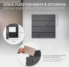 A dark gray mailbox is shown mounted on a textured gray wall. Inset circles highlight the dimensions of the mailbox opening and a hand inserting a letter. Text overlays describe the product's features and dimensions. Anteprima dell’immagine prodotto