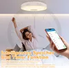 A woman stretching in bed with a smart ceiling light and a smartphone displaying app controls in the foreground. Produktbild-Vorschau