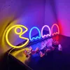 A neon sign depicting Pac-Man and ghosts is displayed on a shelf with flowers. Voir les images du produit