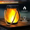 A solar-powered lantern with a flame effect sits on a wooden surface, with marketing text and icons indicating its features. Produktbild-Vorschau