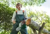 A man is using a cordless chainsaw to cut a log in an outdoor setting. Produktbild-Vorschau