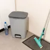 A grey pedal trash can with a blue water bottle next to it, and a mop on a mat. Náhled obrázku produktu