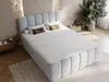 A bedroom scene with a large bed as the central focus, decorated with pillows and a rolled bolster. The room has a modern, minimalist aesthetic with textured walls and wooden flooring. Produktbild-Vorschau
