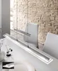 A modern linear pendant light fixture hanging over a white dining table. Produktbild-Vorschau
