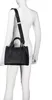 A mannequin wearing a white long-sleeved shirt and a black Valentino handbag. Voir les images du produit