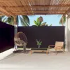An outdoor patio area with a retractable side awning, a hanging chair, and a small coffee table. Produktbild-Vorschau