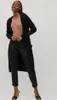 A woman is posing in a studio setting wearing a black cardigan and black pants. Produktbild-Vorschau