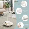 A white round side table with two shelves, placed on a rug in a room with a balcony in the background. The image also includes callouts highlighting product features. Produktbild-Vorschau