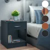 A dark gray nightstand next to a bed, with decorative swatches of different wood finishes and white shown on the right side. Produktbild-Vorschau