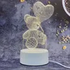 A 3D wireframe teddy bear holding a heart-shaped balloon, illuminated by internal lights, sits on a white base with a power cord. Produktbild-Vorschau